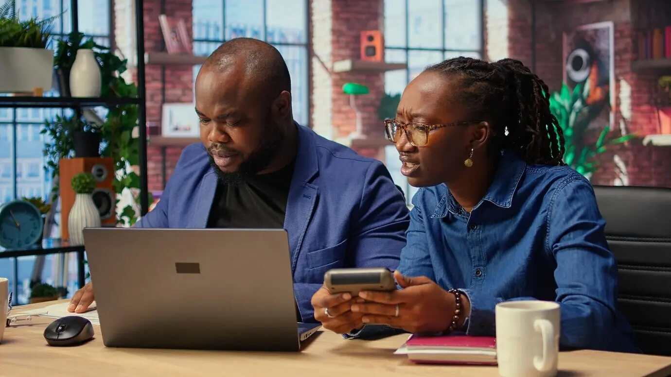 Чернокожие мужчина и женщина анализируют финансовые документы и отслеживают расходы.